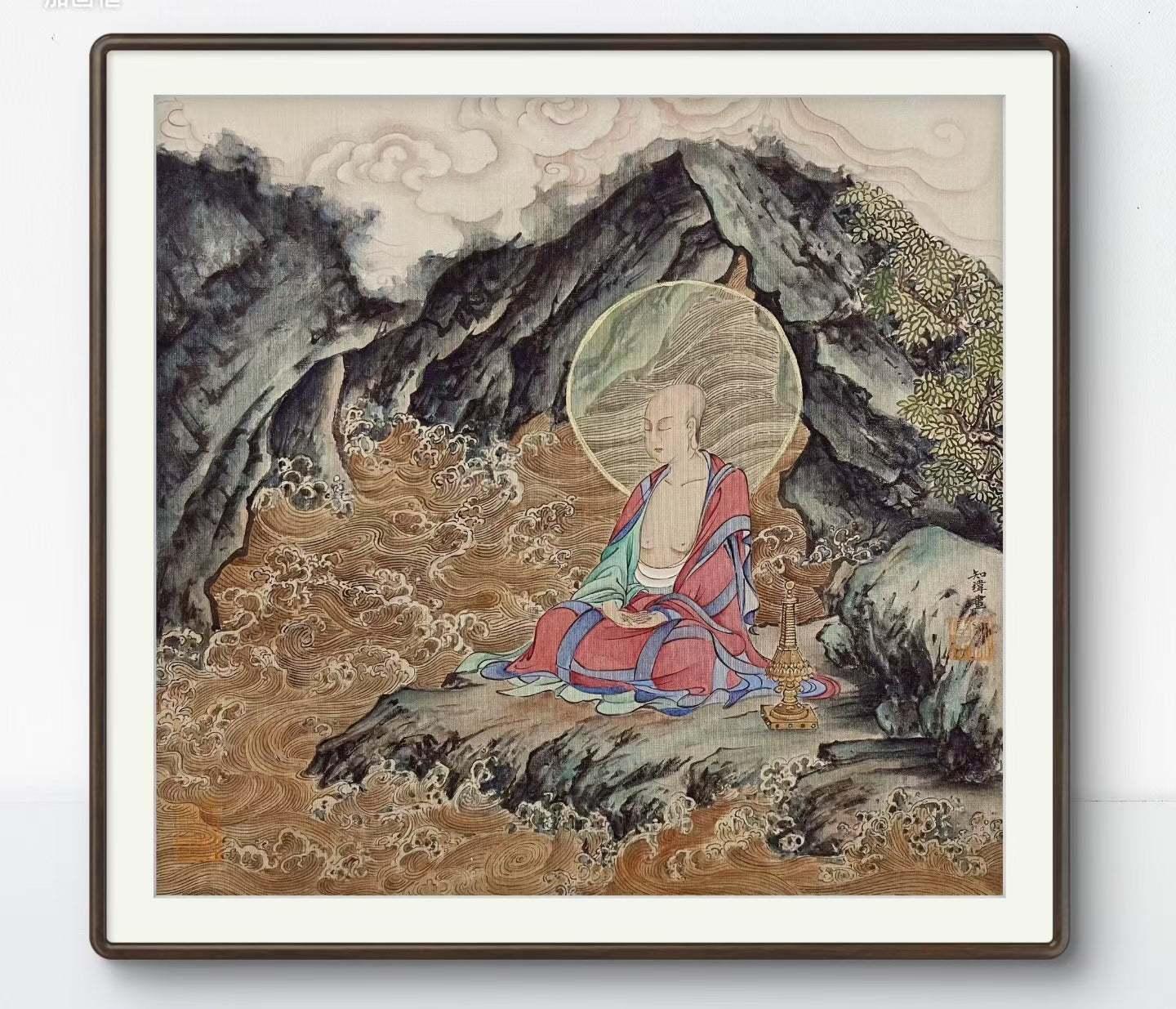 Framed artwork of a seated Buddha with a mountainous landscape